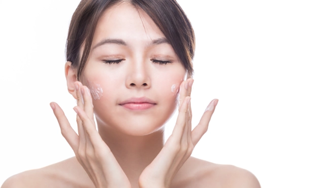 East Asian woman applying skincare to her face
