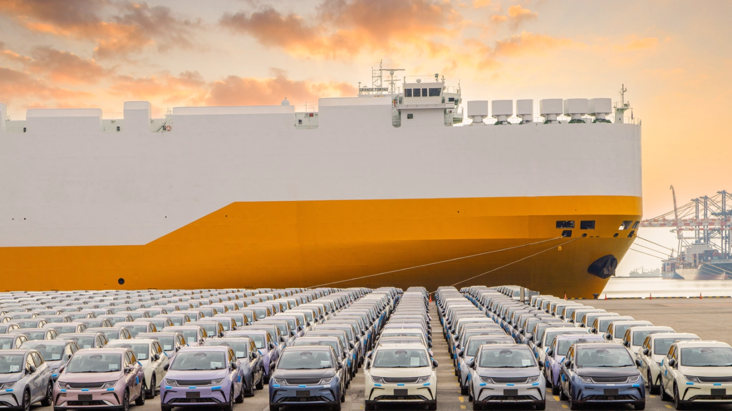 new cars parked in front of a ship in the harbour image
