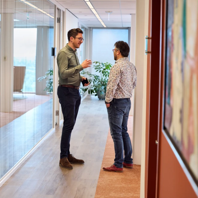 Two colleagues confer briefly in the corridor